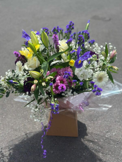 Violet Meadow - A fresh and graceful bouquet filled with rich violet tones, soft whites, gentle pink accents, and touches of sunny yellow. Beautifully wrapped in clear presentation wrap and finished with trailing ribbon, this design has a natural, meadow-inspired feel with plenty of texture and movement. Perfect for birthdays, thank-you gifts, celebrations, or sending a bright and thoughtful gesture.