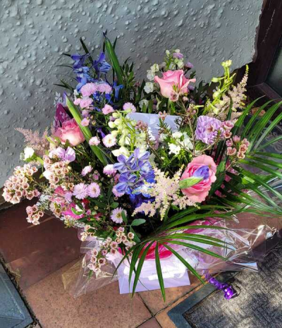 Enchanted Garden - A beautifully whimsical bouquet featuring a soft blend of pastel pinks, gentle purples, creamy whites, and touches of fresh greenery. Designed with a loose, natural style, this arrangement showcases graceful movement and layered textures, enhanced by delicate accents and flowing foliage. Wrapped elegantly and finished with subtle detailing, it’s perfect for heartfelt gifts, celebrations, or adding a touch of romantic charm to any setting.