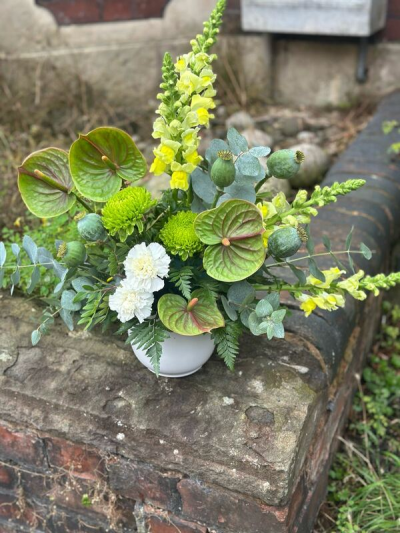 Verdant Woodland Arrangement - A striking, nature-inspired design showcasing a rich palette of fresh greens accented with soft whites and subtle yellow tones. Featuring bold structural elements, textured foliage, and unique natural details, this arrangement has a modern yet organic feel. The combination of varied shapes and tones creates depth and visual interest, while the compact container keeps it stylish and versatile. Perfect for contemporary spaces, thoughtful gifts, or anyone who loves a fresh, earthy aesthetic.