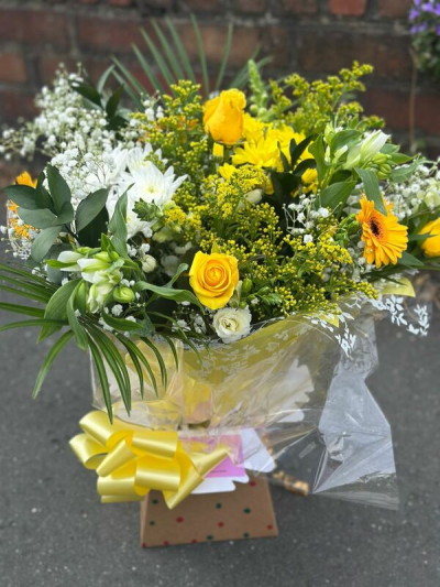 Golden Breeze Bouquet - A fresh and uplifting bouquet filled with radiant golden tones, crisp whites, and vibrant greenery. Designed with a light, airy feel, this arrangement features layered textures and natural movement, creating a bright and cheerful display. Finished with elegant wrapping and a coordinating ribbon, it’s perfect for celebrations, thank-you gifts, or bringing a touch of sunshine into any space.
