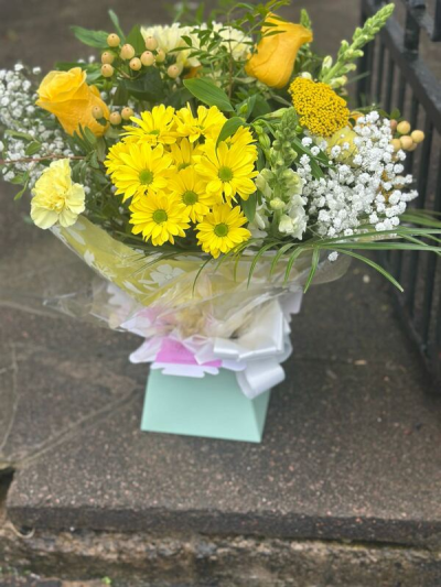 Mellow Yellow - A bright and cheerful bouquet filled with radiant yellow tones, soft whites, and fresh green accents. Designed with a natural, airy style, this arrangement features a mix of textures and gentle movement, creating a light and uplifting feel. Finished with elegant wrap and a coordinating bow, it’s perfect for celebrating happy moments, sending a thoughtful gift, or bringing a burst of sunshine into any space.