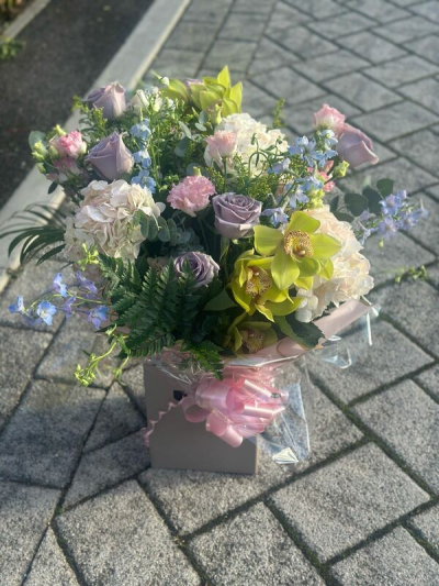 Serenity Garden - A soft and sophisticated bouquet featuring a delicate blend of pastel tones, including gentle lilacs, blush pinks, creamy whites, and fresh green accents. Designed with a loose, garden-inspired style, it showcases graceful movement, varied textures, and a natural, airy feel. Elegantly wrapped and finished with a coordinating ribbon, this arrangement is perfect for thoughtful gifts, celebrations, or bringing a calm and refined beauty to any setting.