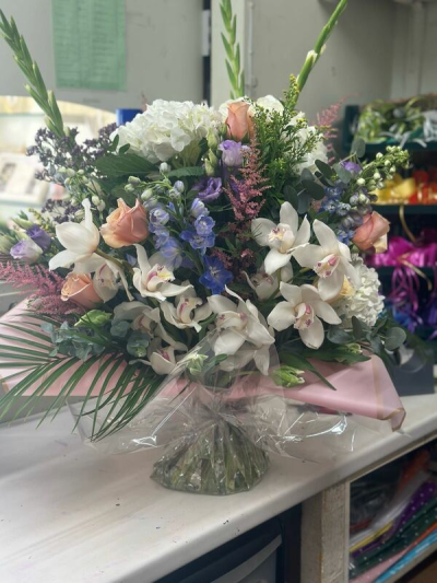 Lavish Love - A graceful and sophisticated arrangement featuring a harmonious blend of soft blush tones, creamy whites, and gentle hints of lavender and blue. Designed with a flowing, organic style, this piece showcases layered textures and lush greenery for depth and movement. Presented in a classic glass vase with a refined wrap detail, it’s perfect for weddings, special celebrations, or adding a touch of timeless elegance to any space.