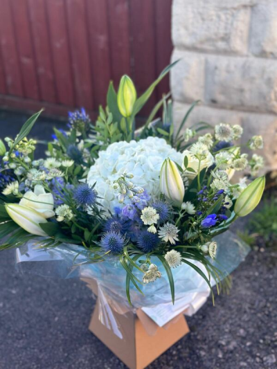 Hedgerow Beauty - A fresh and calming bouquet featuring a serene palette of crisp whites, soft blues, and gentle green tones. Designed with a natural, garden-inspired style, it offers a beautiful mix of textures and airy movement, creating a light and tranquil feel. Lush foliage and delicate accents add depth, while the elegant wrapping completes the look. Perfect for sympathy gestures, thoughtful gifts, or bringing a peaceful touch to any setting.