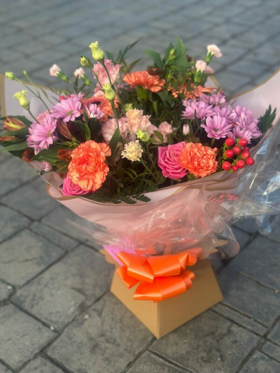 Coral Bliss - A warm and inviting bouquet featuring a vibrant blend of coral, blush pink, and soft peach tones, complemented by fresh greenery and delicate accents. Designed in a relaxed, garden-inspired style, this arrangement offers a natural flow with rich texture and depth. Finished with elegant wrapping and a bold coordinating bow, it’s perfect for celebrations, heartfelt gifts, or adding a cheerful and radiant touch to any occasion.
