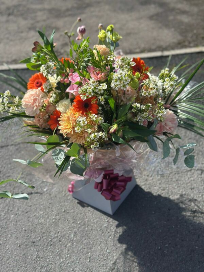Happy Thoughts - A warm and naturally styled arrangement inspired by a sun-drenched garden in full bloom. Featuring a harmonious blend of soft peach, creamy tones, and vibrant orange accents, this design is rich in texture and movement. Delicate filler elements and flowing greenery create an organic, slightly wild feel, while the elegant wrap and decorative bow add a refined finish. Perfect for celebrations, seasonal gifting, or bringing a radiant, rustic charm to any setting.