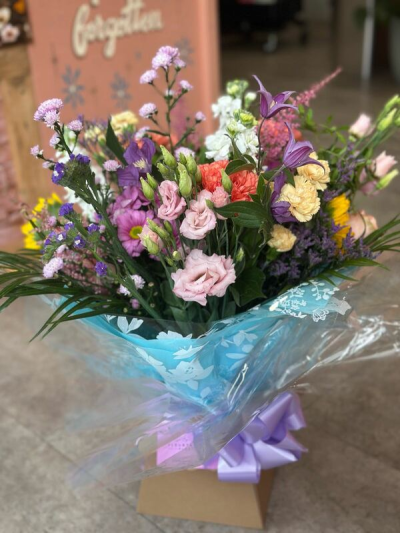 Garden Party - A cheerful and playful bouquet filled with a vibrant mix of soft pastels and bright pops of color. Featuring shades of blush pink, lavender, creamy yellow, and hints of coral, this arrangement is full of texture and lively movement. Designed in a loose, garden-inspired style with fresh greenery and delicate accents, it creates a joyful, just-picked feel. Finished with elegant wrapping and a coordinating ribbon, it’s perfect for celebrations, birthdays, or sending a fun and uplifting gift.