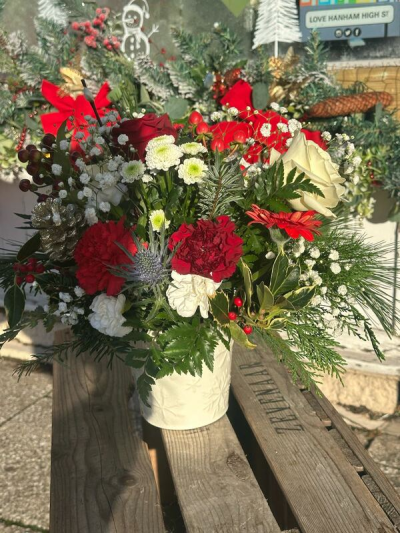 Festive Evergreen Elegance - A rich and seasonal arrangement inspired by classic holiday charm, featuring deep reds, creamy whites, and lush evergreen foliage. Accented with natural textures and subtle festive details, this design brings warmth, depth, and a cozy, woodland feel. Presented in a stylish container, it’s perfect for seasonal décor, celebrations, or gifting a touch of festive cheer and timeless elegance.