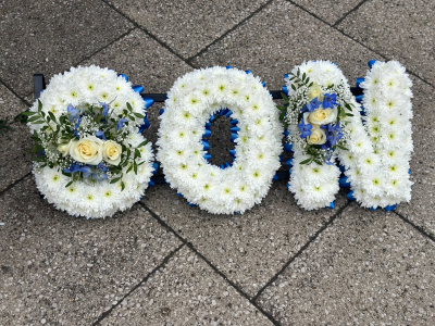 Massed Letters - A beautifully crafted tribute arrangement designed in bold lettering, symbolizing love, remembrance, and a heartfelt farewell. Created with a soft white base and accented with gentle blue tones and fresh greenery, this piece offers a serene and dignified presence. Delicate focal accents add depth and elegance, while the structured design ensures a striking visual impact. Ideal for memorial services, it serves as a meaningful and personal expression of respect and lasting memory.

Can be made in any colours