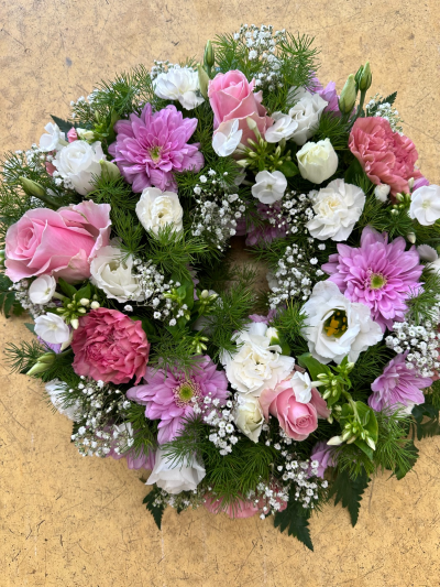 Pink wreath - A soft and graceful circular tribute designed to express love, comfort, and lasting memories. This wreath features a delicate blend of blush pinks and gentle whites, beautifully complemented by fresh greenery for a natural, garden-inspired feel. The airy textures and romantic tones create a sense of peace and tenderness, making it a heartfelt choice for honouring a loved one. Elegant and timeless, it offers a soothing presence during moments of reflection and remembrance.