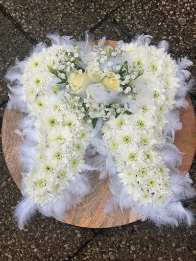 Angel Wings - A graceful and comforting funeral tribute designed in the shape of soft angel wings, symbolising peace, protection, and a gentle farewell. Crafted in calming white tones with delicate textural accents and a light, feathery finish, this arrangement brings a sense of serenity and hope. The central cluster adds a tender focal point, making this a heartfelt piece to honour a loved one and express everlasting love and remembrance.